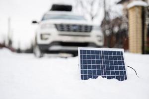 Portable solar panel against SUV car at winter. photo