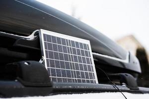 vista de cerca del panel solar portátil cerca del portaequipajes del coche todoterreno en invierno. foto