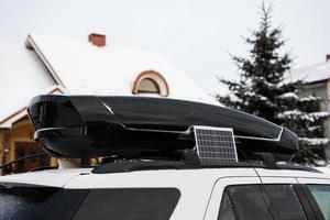 Portable solar panel near roof rack of SUV car at winter. photo
