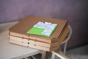 cajas de pizza de cartón con portapapeles de entrega en la cocina en la mesa. foto