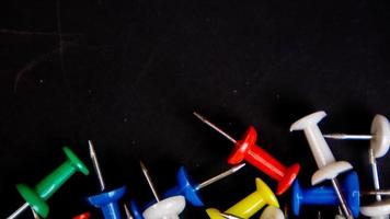 multicolored thumbtacks on a black background photo