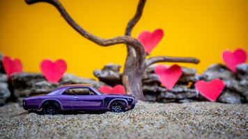 Minahasa, Indonesia  December 2022, toy car with gradient orange background and a heart photo