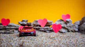 Minahasa, Indonesia  December 2022, toy car with gradient orange background and a heart photo