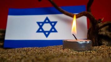 bandera israelí y velas encendidas frente a ella, día de la memoria del holocausto foto