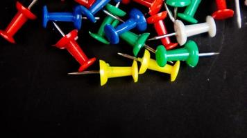 multicolored thumbtacks on a black background photo