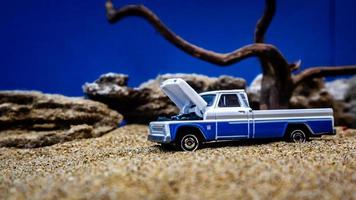 minahasa, indonesia enero de 2023, un coche de juguete en la arena con un fondo de rocas y cielo azul foto