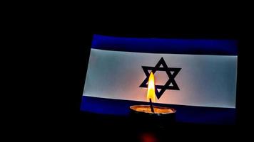 Israeli flag and candles burning in front of it, Holocaust memory day photo