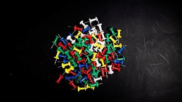 multicolored thumbtacks on a black background photo