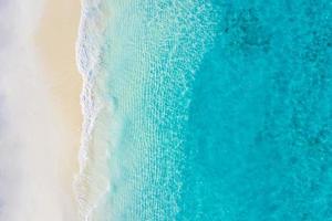 Summer seascape beautiful waves, blue sea water in sunny day. Top view from drone. Sea aerial view, amazing tropical nature background. Beautiful bright sea waves splashing and beach sand sunset light photo