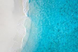 Summer seascape beautiful waves, blue sea water in sunny day. Top view from drone. Sea aerial view, amazing tropical nature background. Beautiful bright sea waves splashing and beach sand sunset light photo