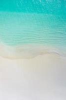 Summer seascape beautiful waves, blue sea water in sunny day. Top view from drone. Sea aerial view, amazing tropical nature background. Beautiful bright sea waves splashing and beach sand sunset light photo