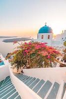 Oia at sunset, Santorini island, Greece. Artistic sunset landscape with beautiful flowers and stone stairs with sea view. Fantastic summer vacation and holiday concept. Peaceful nature scenery photo