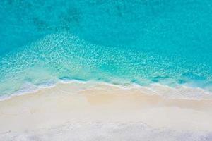 Summer seascape beautiful waves, blue sea water in sunny day. Top view from drone. Sea aerial view, amazing tropical nature background. Beautiful bright sea waves splashing and beach sand sunset light photo