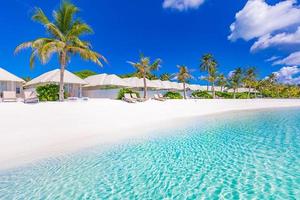 villas de playa en maldivas, viajes de verano de lujo y fondo de vacaciones. increíble mar azul y palmeras bajo el cielo azul. paisaje tropical y playa exótica. destino de vacaciones de verano o luna de miel foto