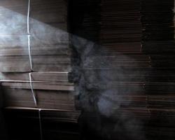 smoke in a streak of light against the background of stacked cardboard boxes in a warehouse photo