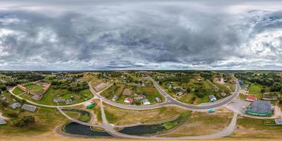 vista panorámica aérea completa esférica hdri 360 sobre pueblo verde con sector de desarrollo privado con casas de campo en proyección equirectangular. usar como reemplazo del cielo para tomas de drones foto