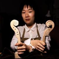 young chinese woman violin maker showing the neck of the violins under construction photo