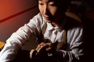 young Chinese female violin maker working on the neck of the violin under construction photo