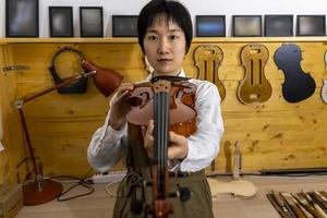 young Chinese violin maker at work in her workshop photo