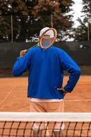 a retired tennis player dressed in sportswear posing with his back to the camera on a clay tennis court photo