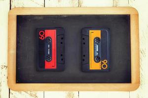 pair of vintage audio cassettes over a black chalkboard photo