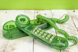 green colorful vintage telephone over a white wooden table photo