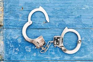 chrome handcuffs on blue wooden background photo