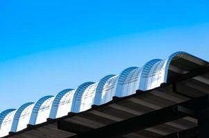 Metal sheet roof curve on blue sky,Modern construction. Metal ribbed arch-span roof covering photo