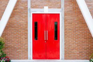 Red modern door with long stainless handle on brick wall at modern building photo