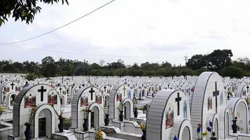 The public cemetery contains identical white ceramic graves with flowers. photo