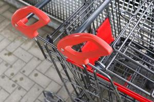 manijas de carritos de compras en primer plano frente a un supermercado. foto