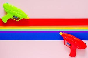 Two water gun with colorful cutting paper for Songkran festival celebration on pink color background. Minimal holiday concept. photo