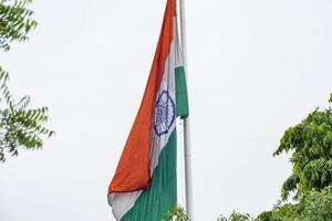 India flag flying high at Connaught Place with pride in blue sky, India flag fluttering, Indian Flag on Independence Day and Republic Day of India, tilt up shot, Waving Indian flag, Har Ghar Tiranga photo