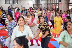 Delhi, India, June 19 2022 -Group Yoga Aerobics session for people of different age groups in Balaji Temple, Vivek Vihar, International Yoga Day, Big group of adults attending aerobics class in temple photo