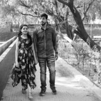 Indian couple posing for maternity baby shoot. The couple is posing in a lawn with green grass and the woman is falunting her baby bump in Lodhi Garden in New Delhi, India - Black and White photo