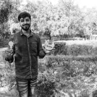 Indian couple posing for maternity baby shoot. The couple is posing in a lawn with green grass and the woman is falunting her baby bump in Lodhi Garden in New Delhi, India - Black and White photo