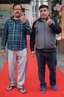 New Delhi, India - December 04 2022 - Unidentified people showing their ink-marked fingers after casting votes in front of polling booth of east Delhi area for MCD local body Elections 2022 photo