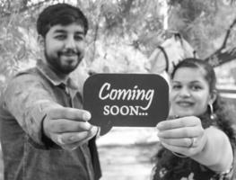 pareja india posando para una sesión de fotos de maternidad. la pareja está posando en un césped con hierba verde y la mujer está faluntando su panza en el jardín de lodhi en nueva delhi, india - blanco y negro