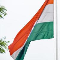 India flag flying high at Connaught Place with pride in blue sky, India flag fluttering, Indian Flag on Independence Day and Republic Day of India, tilt up shot, Waving Indian flag, Har Ghar Tiranga photo