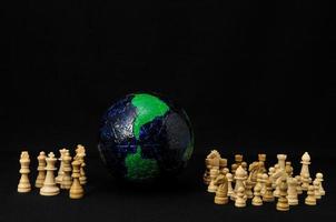 Chess figures and a globe on black background photo