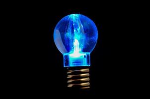 Blue lightbulb on black background photo