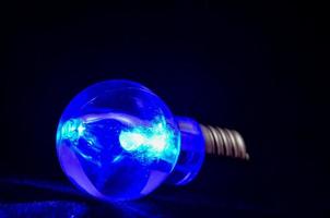 Blue light bulb on black background photo