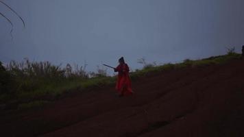 eine chinesische frau, die während des dunklen morgens eine stockkampfkunst in einem roten kostüm übt video