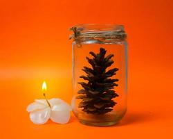 Christmas gift glass containing pine with candle isolated on orange background. new year concept photo