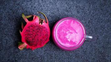 Top vie of a glass of dragon fruit juice with a Slice of fresh dragon fruit on dark background. Healthy drink concept photo