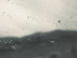 Abstract background of rain drops on glass window with moody tone photo