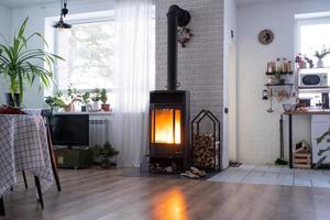 Black stove, fireplace in interior of house in loft style. Alternative eco-friendly heating, warm cozy room at home, burning wood photo