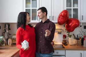 Man and woman in love date at home in kitchen with keys of house. Valentine's Day, happy couple, love story. Love nest, mortgage, relocation, purchase, real estate, housing for young family photo