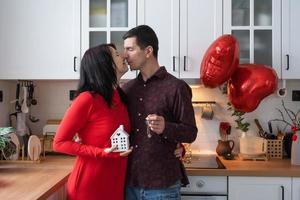 Man and woman in love date at home in kitchen with keys of house. Valentine's Day, happy couple, love story. Love nest, mortgage, relocation, purchase, real estate, housing for young family photo