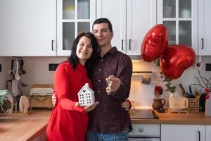 Man and woman in love date at home in kitchen with keys of house. Valentine's Day, happy couple, love story. Love nest, mortgage, relocation, purchase, real estate, housing for young family photo